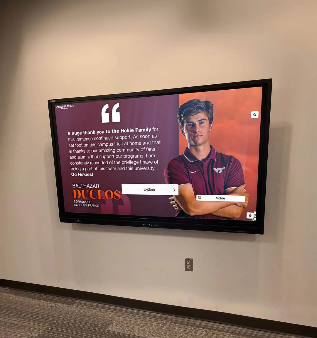 University recognition wall celebrating student achievement across academic and extracurricular programs Virginia Tech wall display with student athlete in maroon polo